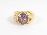 gros plan d'une bague en or avec une pierre violette