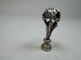 a silver vase with a flower on it on a table