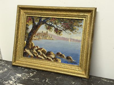 une peinture à l'huile représentant un arbre au bord de l'eau, dans un cadre doré