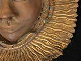 a gold sculpture of a woman ' s face on a black surface