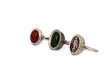 three different colored stone stud earrings sitting on top of a white surface