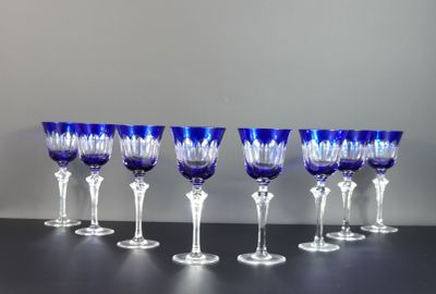 six verres à vin bleus sont alignés sur une table noire