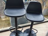 une paire de tabourets de bar en cuir noir devant une grande fenêtre