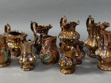 six pieces of antique brass vases are lined up on a gray surface