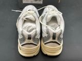 pair of white and gray sneakers on a black surface with a price tag