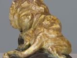 statue of a lion on a rock on a white surface