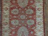 a red and beige rug on a wooden floor