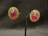 pair of gold and pink stone earrings on a stand