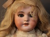 a close up of a doll with blonde hair and a white dress