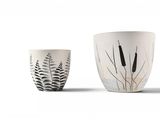 two white cups with black and white designs on them sitting next to each other