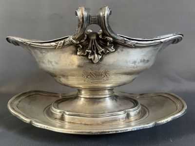 an antique silver plate with a bowl on it on a gray surface