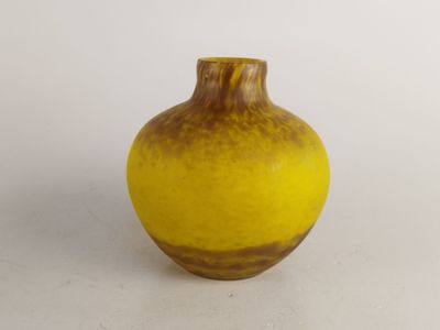 un vase jaune et marron posé sur une surface blanche
