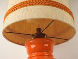 an orange lamp with a white shade on it