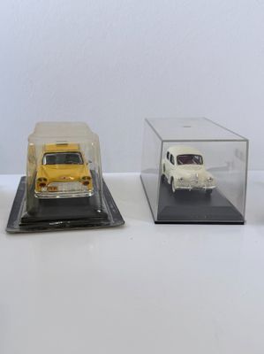 trois modèles réduits de voitures sont exposés dans une vitrine posée sur une surface blanche
