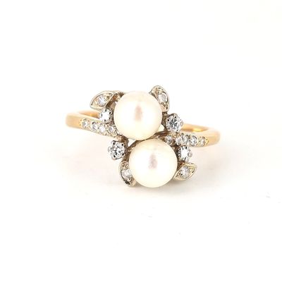 a close up of a white pearl and diamond ring on a white surface