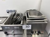 several stainless steel pans are lined up on a table