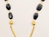 a gold necklace with black beads and a gold chain