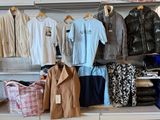 de nombreuses chemises et pantalons suspendus à un portant dans un magasin