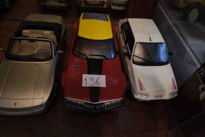 Plusieurs petites voitures sont alignées sur une table dans une vitrine.