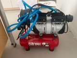 a red air compressor sitting on the floor in a room