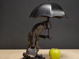 a statue of a man holding an umbrella next to an apple