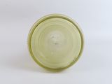 a green glass cup with a white lid sitting on a white surface