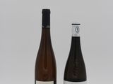 two bottles of wine sitting next to each other on a white surface