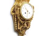 une horloge dorée sur un mur blanc, avec un fond blanc