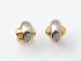 une paire de boucles d'oreilles en or et en argent posées sur une surface blanche