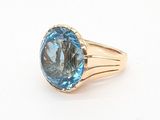 une photo d'une bague sertie d'une topaze bleue posée sur une surface blanche