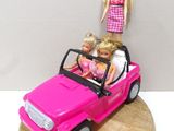 une petite voiture rose avec une poupée Barbie assise dessus
