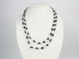 un gros plan d'un collier porté par un mannequin, composé de perles noires et blanches