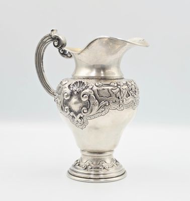 an antique silver plated pitcher on a white background