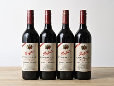 three bottles of red wine sitting on top of a wooden table