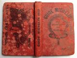 an old book with a red cover sitting on top of a table