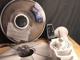 a table with a fan, remote and a phone on it