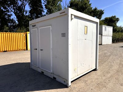 a white portable toilet sitting in the middle of a dirt field