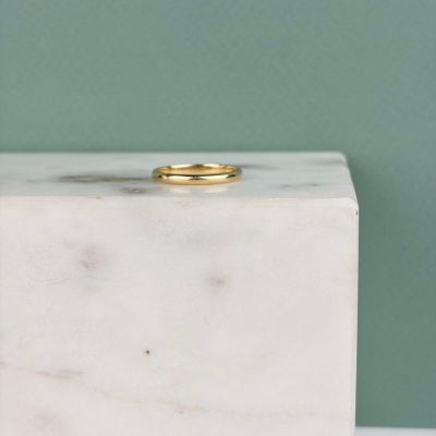 une photo d'une bague en or posée sur un bloc de marbre blanc