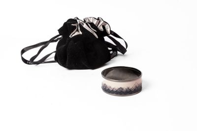 un petit sac et une bague posés sur une surface blanche