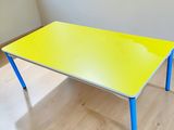 une table jaune aux pieds bleus dans une pièce