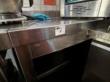 plan de travail en acier inoxydable avec four et lave-vaisselle dans une cuisine professionnelle