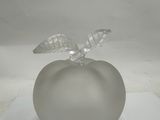 a glass apple with a leaf on it on a white surface
