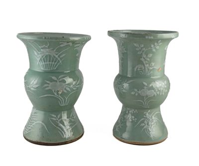 deux vases verts posés l'un à côté de l'autre sur une surface blanche