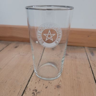 a glass with a pentagram on it sitting on a wooden table