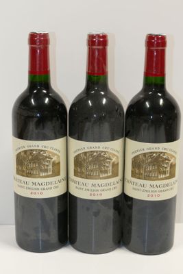 trois bouteilles de vin rouge sont alignées sur une surface blanche