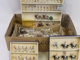 quatre boîtes contenant des figurines miniatures représentant des chevaux et des jockeys