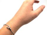 a hand that is holding a silver bracelet on it ' s wrist