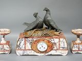 two birds sitting on top of a clock with candles