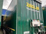 a large green container truck parked in a parking lot