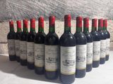 several bottles of wine are lined up in a row in front of a stone wall